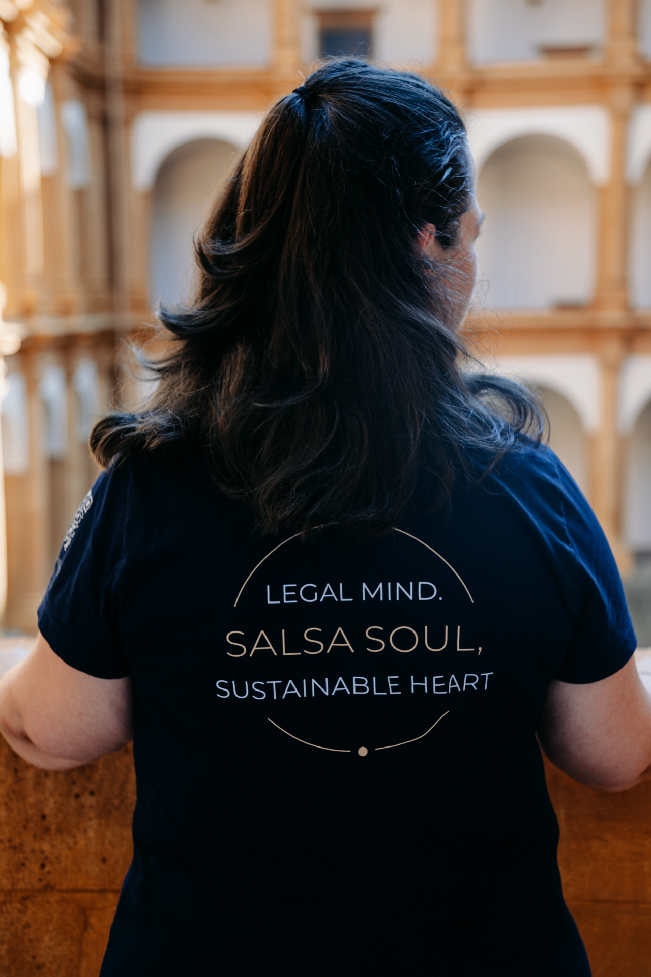 Michaela Fröhlich von hinten, trägt ein T-Shirt mit dem Leitsatz "Legal Mind. Salsa Soul. Sustainable Heart."